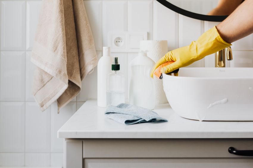 Reinigung eines Waschbeckens mit Schwamm und Handschuhen