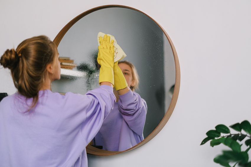 Reinigung eines Wandspiegels mit Handschuhen