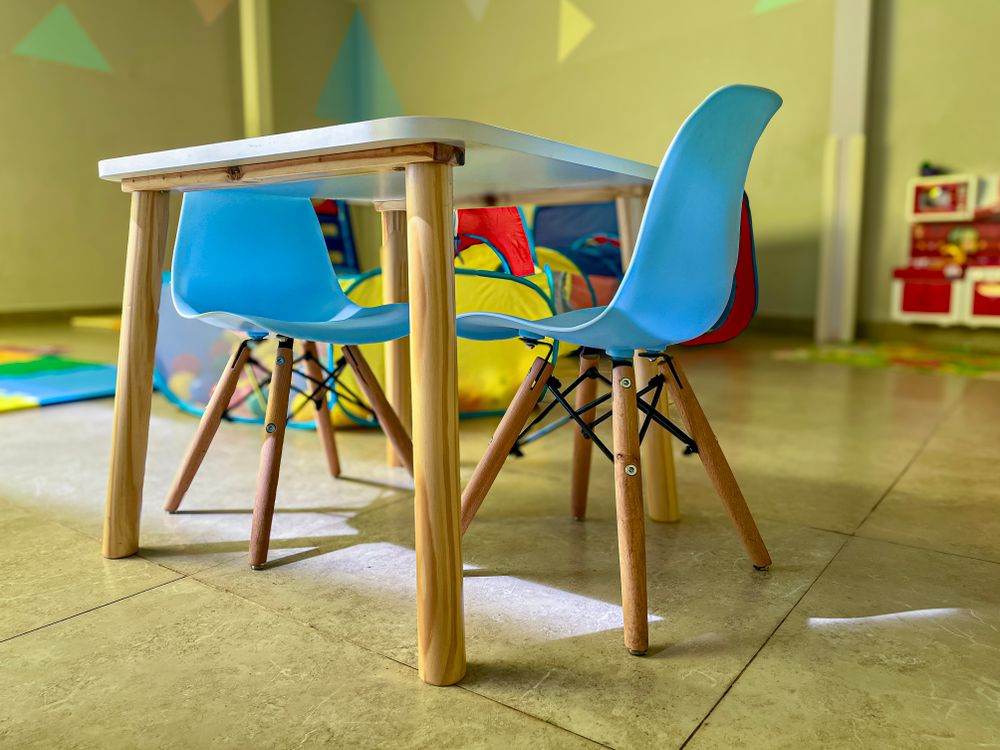 Spielbereich mit kleinen bunten Stühlen und einem Tisch